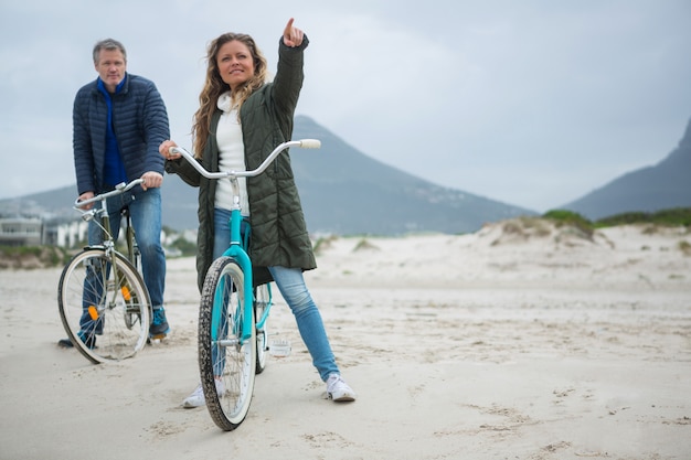 Coppia in bicicletta che punta a distanza sulla spiaggia