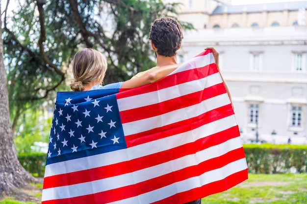 Coppia in città con la bandiera degli Stati Uniti ragazzo e ragazza sulla schiena Patrioti orgogliosi del giorno dell'indipendenza della loro nazione