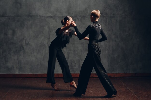 Coppia in costumi neri che ballano nella danza della rumba da sala da ballo.