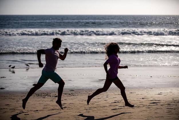 Coppia in esecuzione sulla spiaggia. Sport e stile di vita sano, amici silhouette che fanno jogging al tramonto sulla spiaggia.