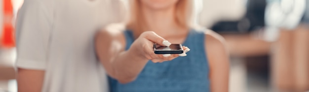 Coppia in piedi nel negozio di tecnologia. Telecomando in mano da ragazza per tv al plasma. Nuovo concetto di tecnologie.