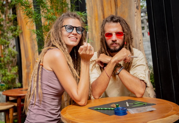 Coppia in stile hippie che fuma sigarette con marijuana medica