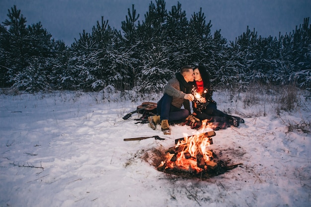 Coppia in una foresta invernale con Sparklers per Festive Mood.