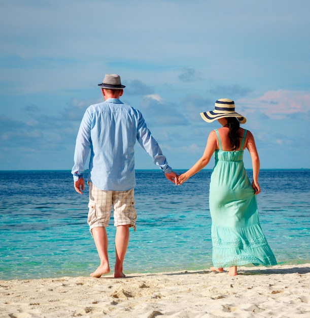 Coppia in vacanza camminando su una spiaggia tropicale delle Maldive. Uomo e donna passeggiata romantica sulla spiaggia.