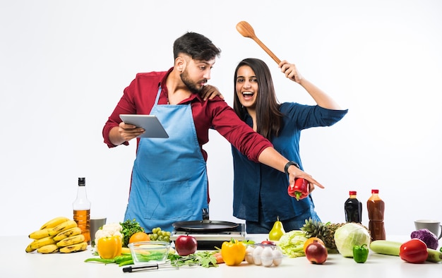 Coppia indiana in cucina - Giovane bella moglie asiatica che si diverte a cucinare con il marito con un sacco di frutta e verdura fresca