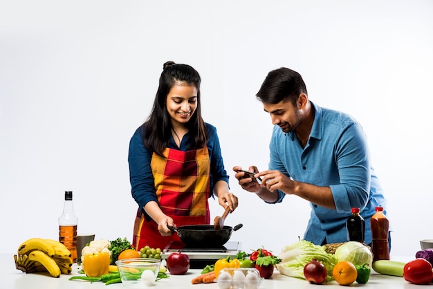 Coppia indiana in cucina - Giovane bella moglie asiatica che si diverte a cucinare con il marito con un sacco di frutta e verdura fresca