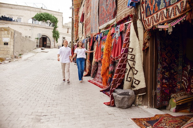 Coppia innamorata acquista un tappeto e tessuti fatti a mano in un mercato orientale in Turchia. Abbracci e volti allegri e felici di uomini e donne