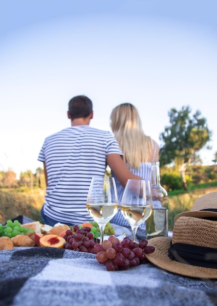 Coppia innamorata che beve vino durante un picnic. Messa a fuoco selettiva