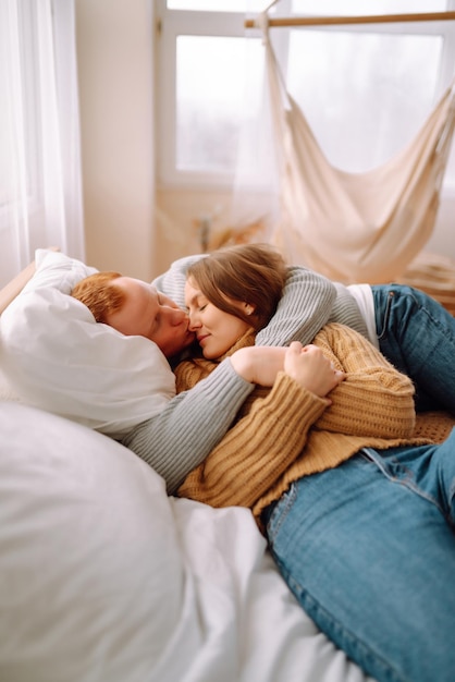 Coppia innamorata che si rilassa a casa sul letto mentre si abbracciano Concetto di vacanza di San Valentino