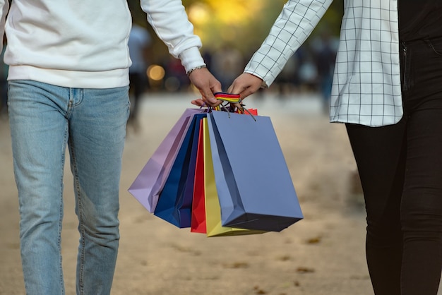 Coppia innamorata porta borse della spesa di carta multicolore. Shopping insieme.