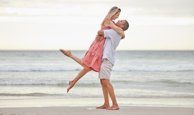 Coppia interrazziale amore e abbraccio su una spiaggia vicino all'acqua in vacanza vacanza nella natura Uomo e donna in una relazione gioiosa affetto insieme dall'oceano nella felicità per la vita all'aria aperta