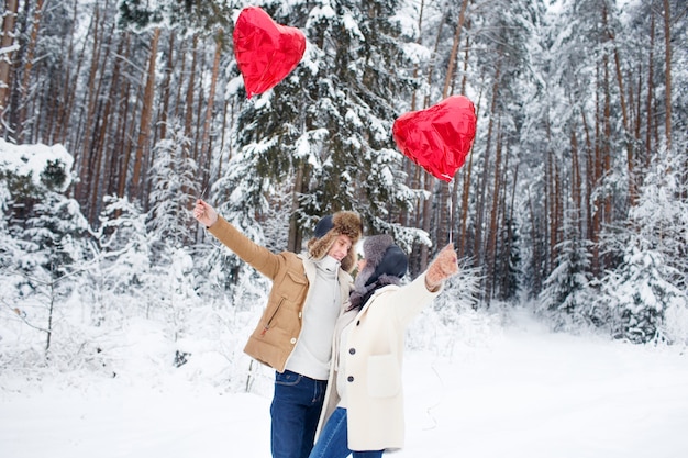 Coppia invernale innamorata. Ragazzo e ragazza che abbracciano in inverno La neve e la foresta fatata con palloncini.