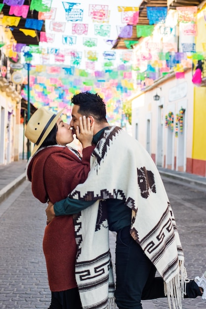 Coppia ispanica che si bacia in una colorata strada messicana