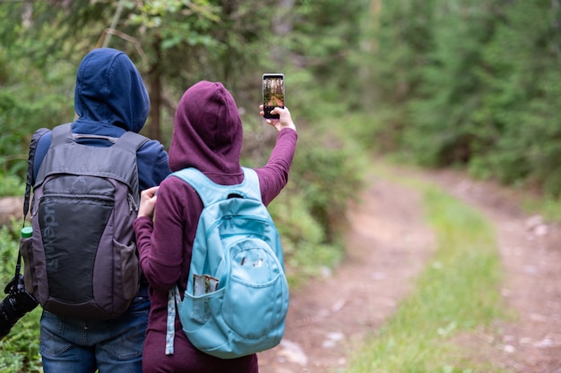 coppia itinerante che cattura foto del paesaggio forestale con lo smartphone