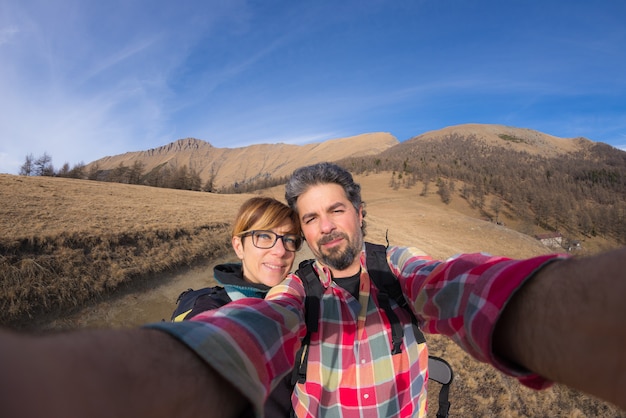 Coppia la presa del selfie nelle montagne dall'obiettivo di fisheye