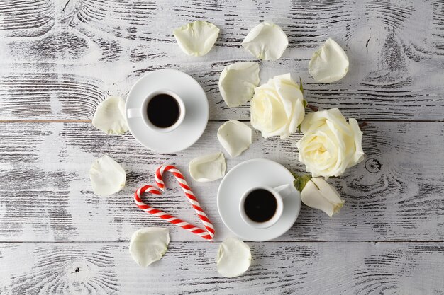 Coppia le tazze bianche con la decorazione dai cuori rossi sulla tavola di legno. Concetto di celebrazione di San Valentino