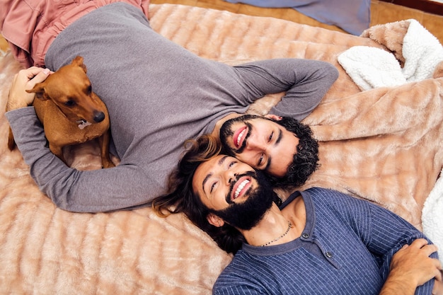 Coppia maschile sdraiata con il loro cane sul letto