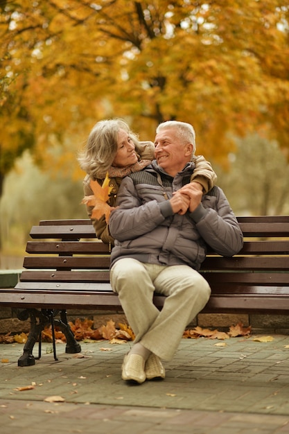 Coppia matura romantica seduta nel parco in autunno