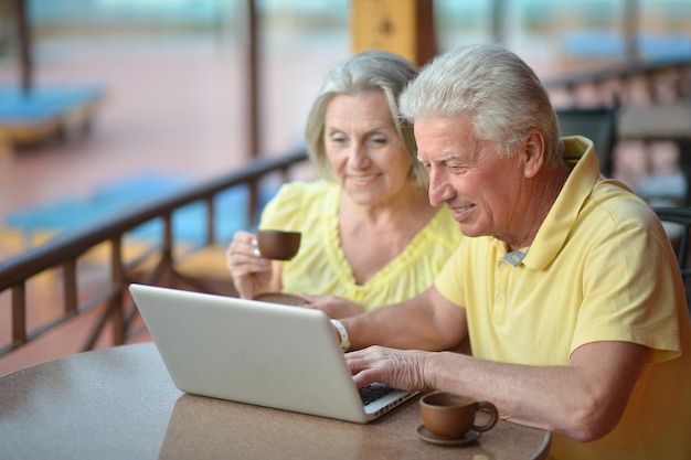 Coppia matura seduta con laptop in hotel