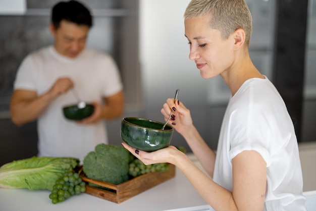 Coppia multirazziale che mangia insalata in cucina a casa