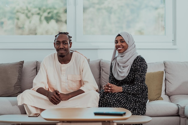 Coppia musulmana africana a casa durante il Ramadan che legge il libro sull'Islam dell'agrifoglio del Corano. Foto di alta qualità