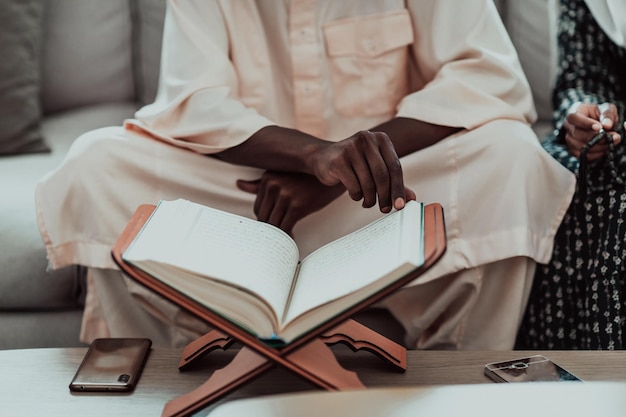 Coppia musulmana africana a casa durante il Ramadan che legge il libro sull'Islam dell'agrifoglio del Corano. Foto di alta qualità