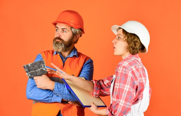 Coppia pensante. rinnovamento e concetto di persone. Le coppie del costruttore guardano i piani domestici. coppia guardando un progetto. donna e uomo indossano l'elmetto protettivo di sicurezza. famiglia in piedi all'interno della casa in costruzione.