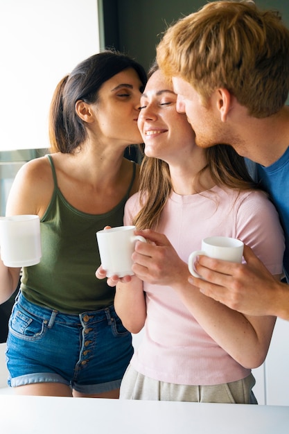 Coppia poliamorosa a casa che mangia insieme un caffè