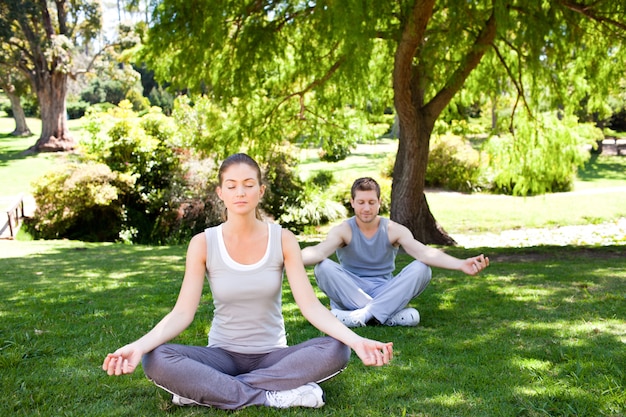 Coppia praticando yoga nel parco