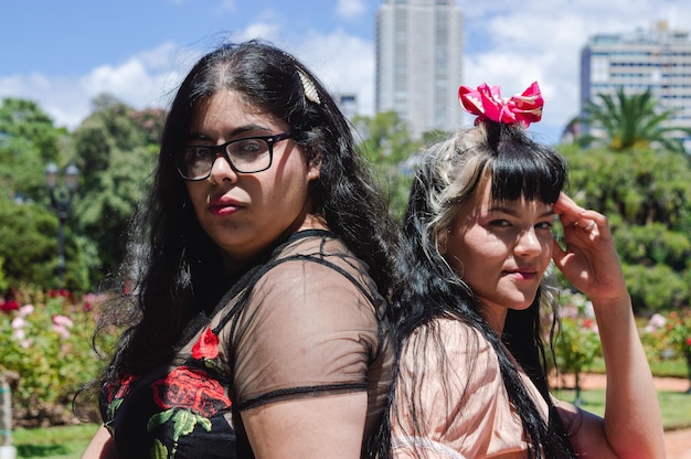 Coppia ritratto di due giovani donne latine caucasiche fuori nel parco insieme schiena contro schiena