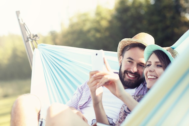 coppia romantica che utilizza smartphone in amaca