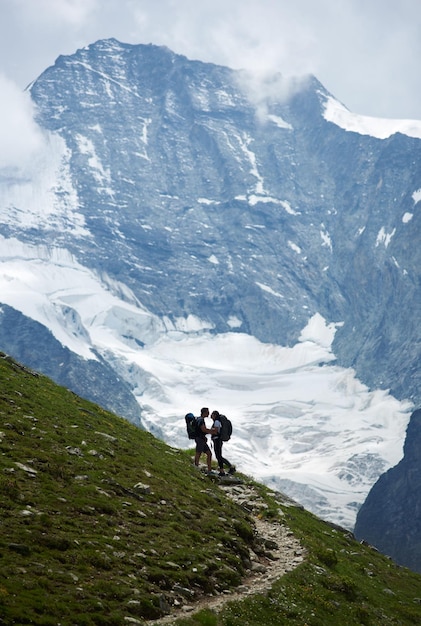 Coppia romantica in piedi su un prato verde a sfondo roccioso delle Alpi svizzere