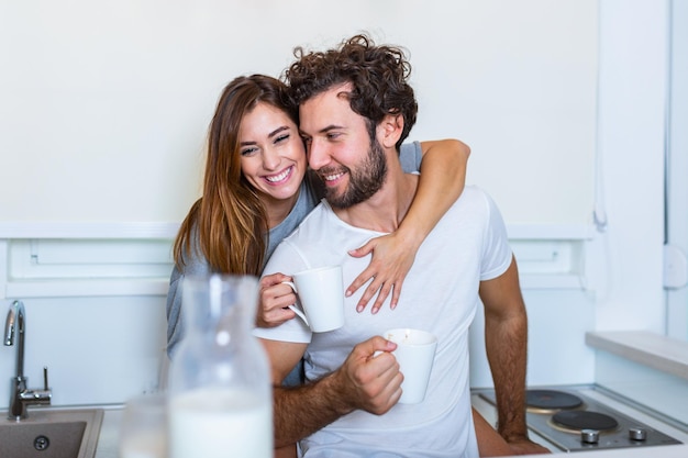 Coppia romantica innamorata che trascorre del tempo insieme in cucina. Carina giovane coppia che beve caffè in cucina e si gode la mattinata insieme