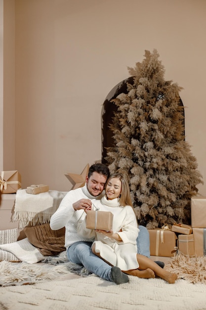 Coppia romantica seduta su un pavimento vicino all'albero di Natale a casa