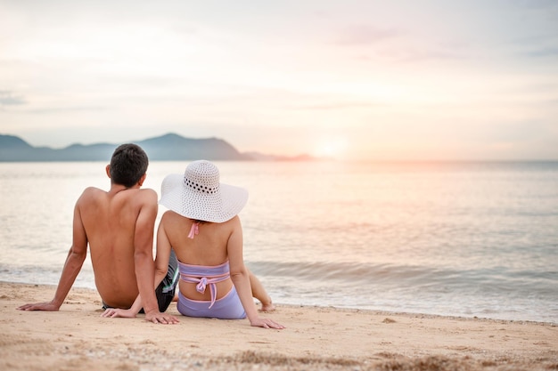 Coppia romantica seduta sulla spiaggia e godersi la splendida vista sul mareamore e concetti di San Valentinoconcetto di vacanza estiva