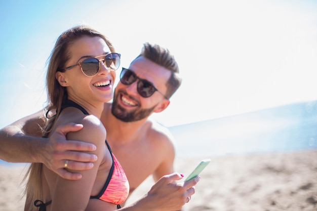 Coppia romantica sfogliando le loro foto sulla spiaggia