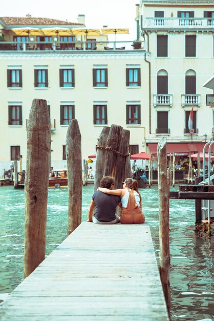 Coppia seduta al molo guardando il Canal Grande a parlare