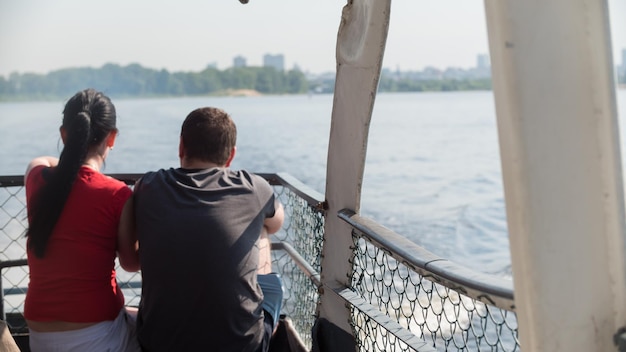 Coppia seduta su una barca turistica e guardando l'acqua, vista posteriore