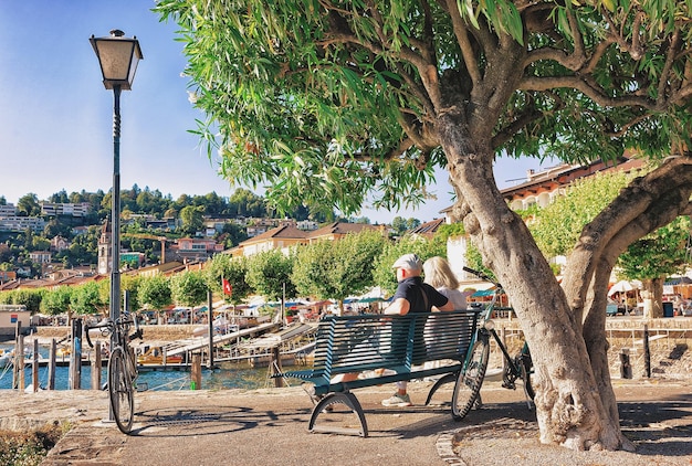 Coppia seduta sulla panchina sul lungomare del lussuoso resort di Ascona sul Lago Maggiore del Canton Ticino in Svizzera.