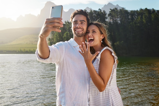 Coppia selfie natura e fidanzamento in riva al lago per celebrare la felicità ed eccitato per il futuro Uomo donna e fotografia per foto del profilo sui social media e romanticismo con proposta d'amore e obiettivi