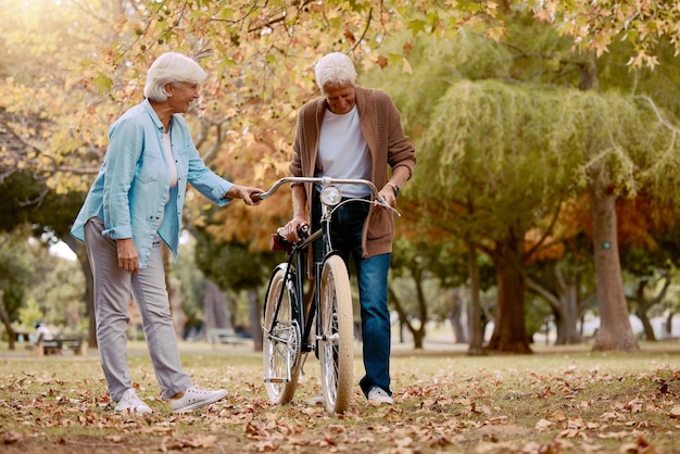 Coppia senior a piedi e in bicicletta nel parco naturale insieme per data romace tempo di qualità e relax libertà all'aperto Amore supporto cura e passeggiata estiva per la pensione uomo e donna felici con la bicicletta