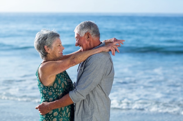 Coppia senior abbracciando in spiaggia