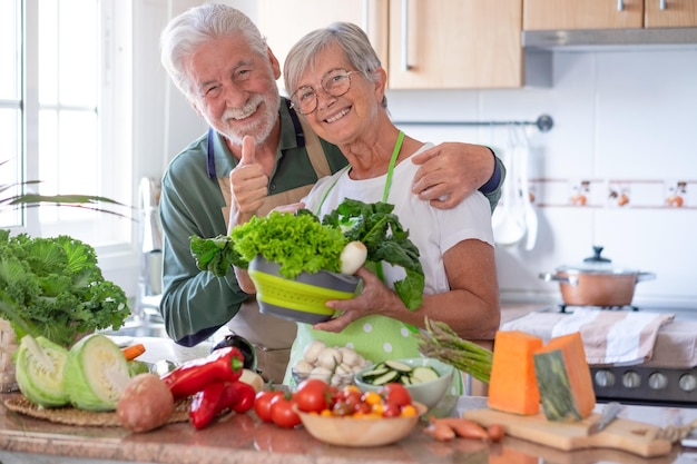 Coppia senior attraente che prepara insieme le verdure nella cucina domestica Anziani caucasici che godono di un'alimentazione sana