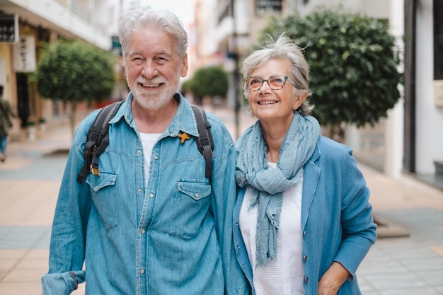 Coppia senior caucasica adulta sorridente attiva felice che cammina nella città tenendosi per mano come turisti