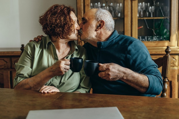 Coppia senior che beve caffè e si bacia a casa