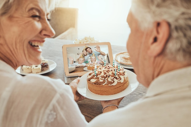 Coppia senior e videochiamata di buon compleanno a casa con una torta famiglia e felicità durante la celebrazione Gli anziani sorridono e si congratulano per la giornata festiva in pensione con amore, cura e sostegno