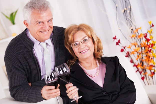 Coppia senior in interni domestici godendo in un bicchiere di vino.