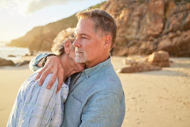 Coppia senior in spiaggia e abbraccio di persone mature con amore e matrimonio sull'oceano Vacanze estive in pensione e vacanze al mare di un uomo e una donna insieme che sentono amore e sostegno nella natura sulla sabbia