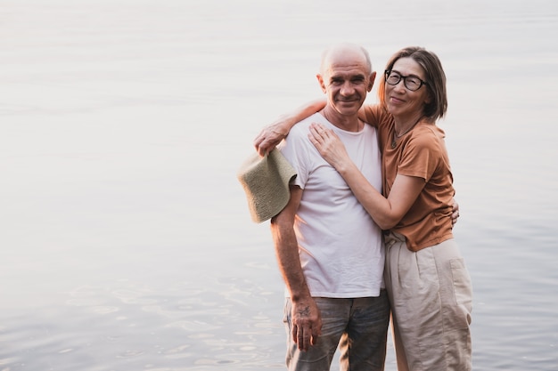 Coppia senior innamorata che abbraccia e sorride in riva al mare