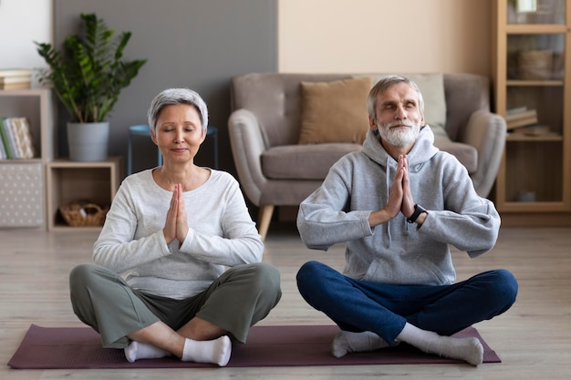 Coppia senior meditando a casa